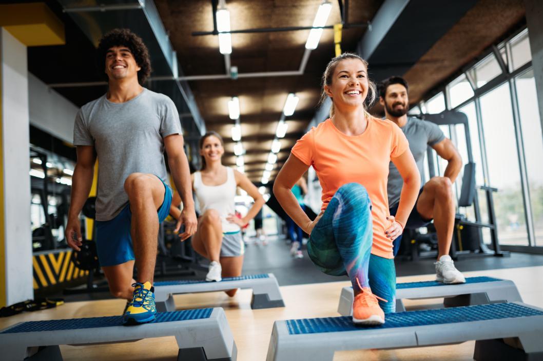 Cours collectif femmes et hommes en train de réaliser des exercices sur stepper. 